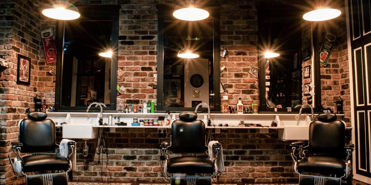 Barbershop interior in Cardiff with three black leather barber chairs against a brick wall