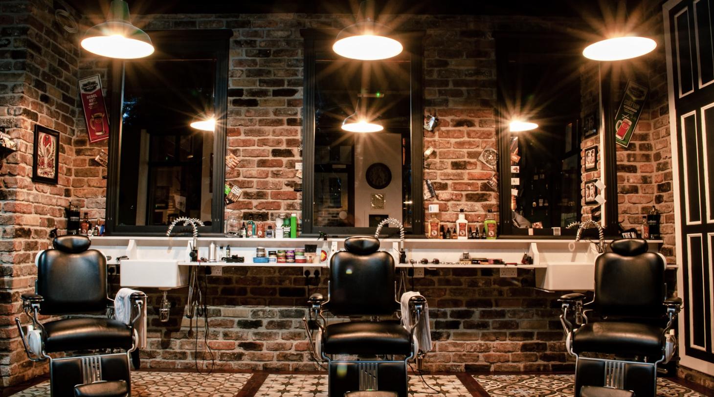 Barbershop interior in Cardiff with three black leather barber chairs against a brick wall